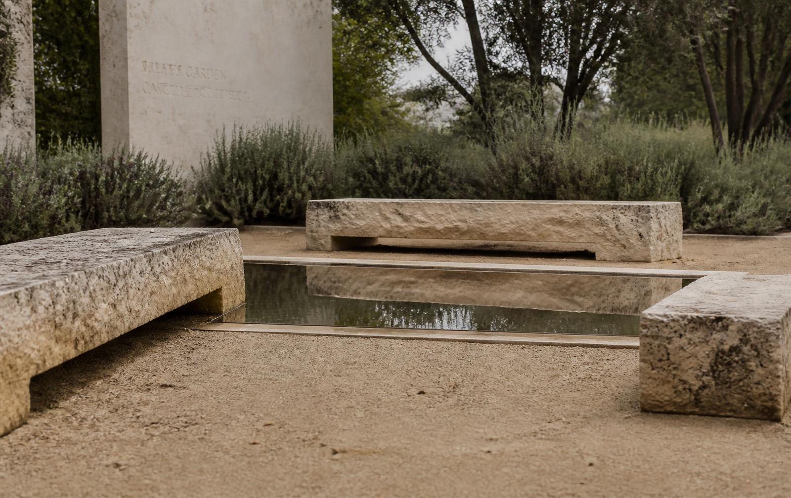 Weathered stone benches around a still reflecting pool in a quiet garden